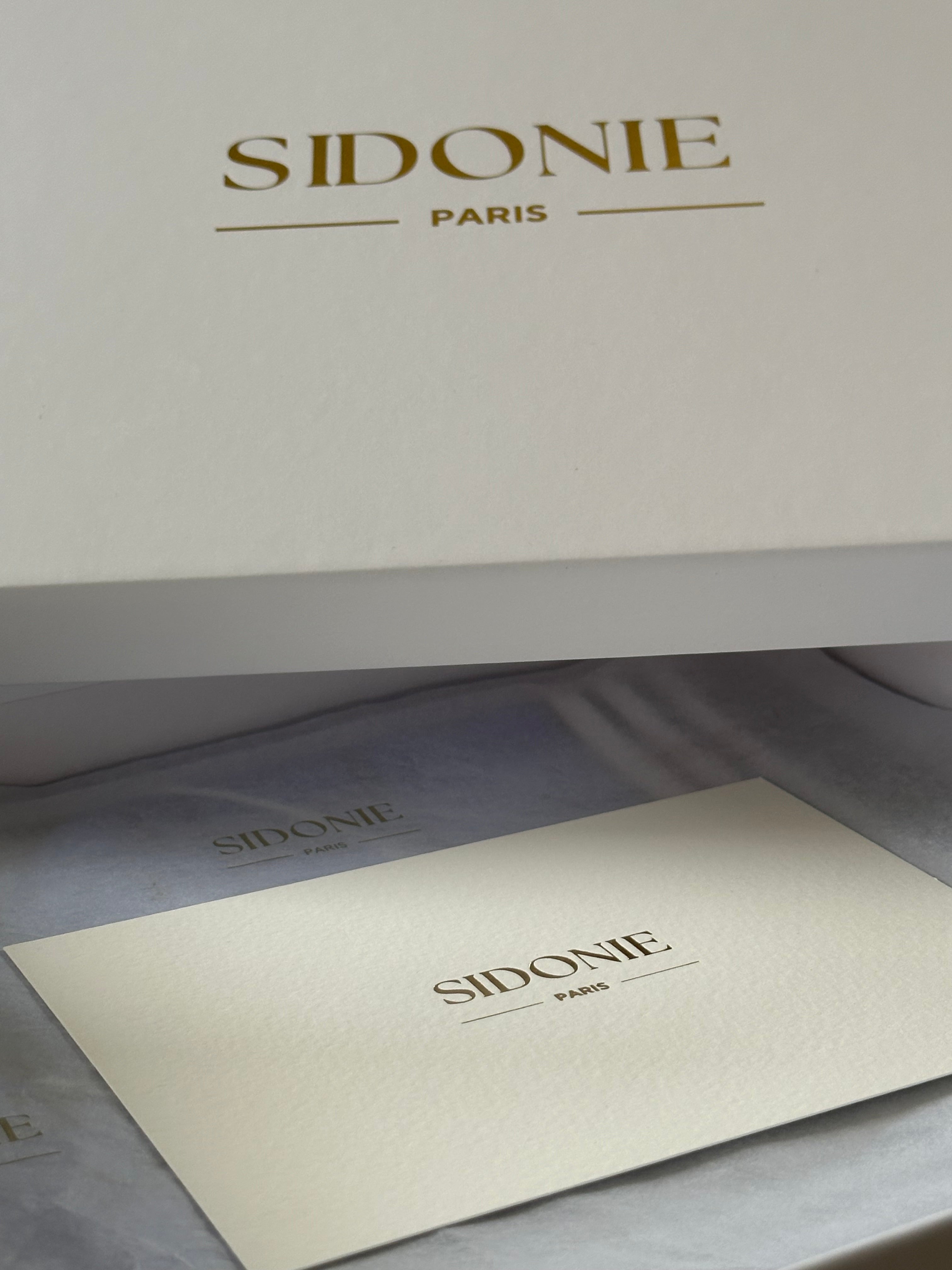 Emballage luxueux de SIDONIE PARIS pour foulard en soie, avec une boîte blanche texturée, un logo doré et un papier de soie délicat accompagné d'une carte.